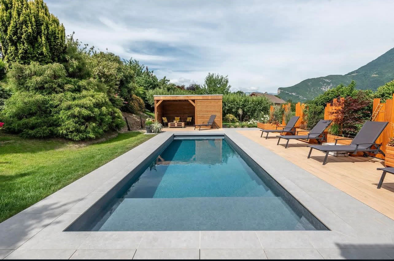 Conception et construction d'une piscine sur mesure avec plage immergée, terrasse en bois, et contour en carrelage, OMH Argonay