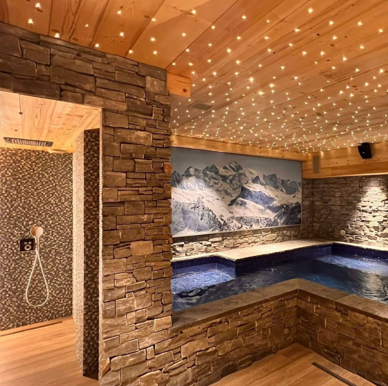 Piscine intérieure personnalisée avec revêtement en pierre et éclairage, et espace douche, OMH Argonay